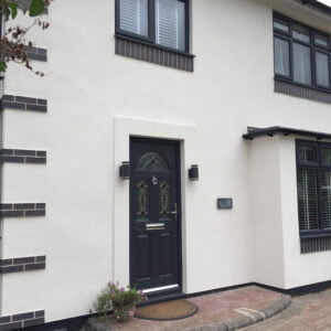 A white rendered house with brick corner quoin detail at the corners of the house and soldier courses in blue brick below the windows.