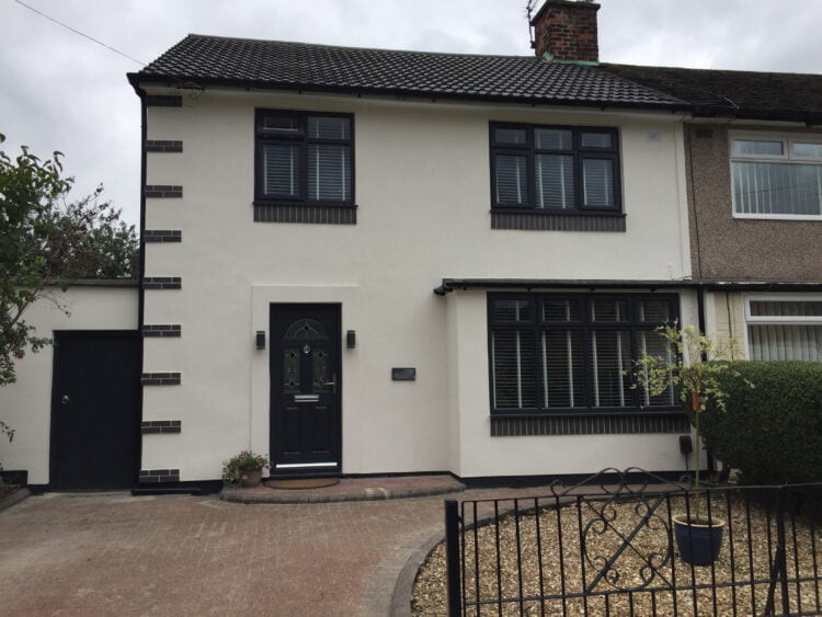 A white rendered house with brick corner quoin detail at the corners of the house and soldier courses in blue brick below the windows.