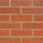 A display panel image of bricks laid in stagger bond. The brick slips are a mid red, roll textured and sanded finish. The bricks are pointed in a mid sandstone mortar