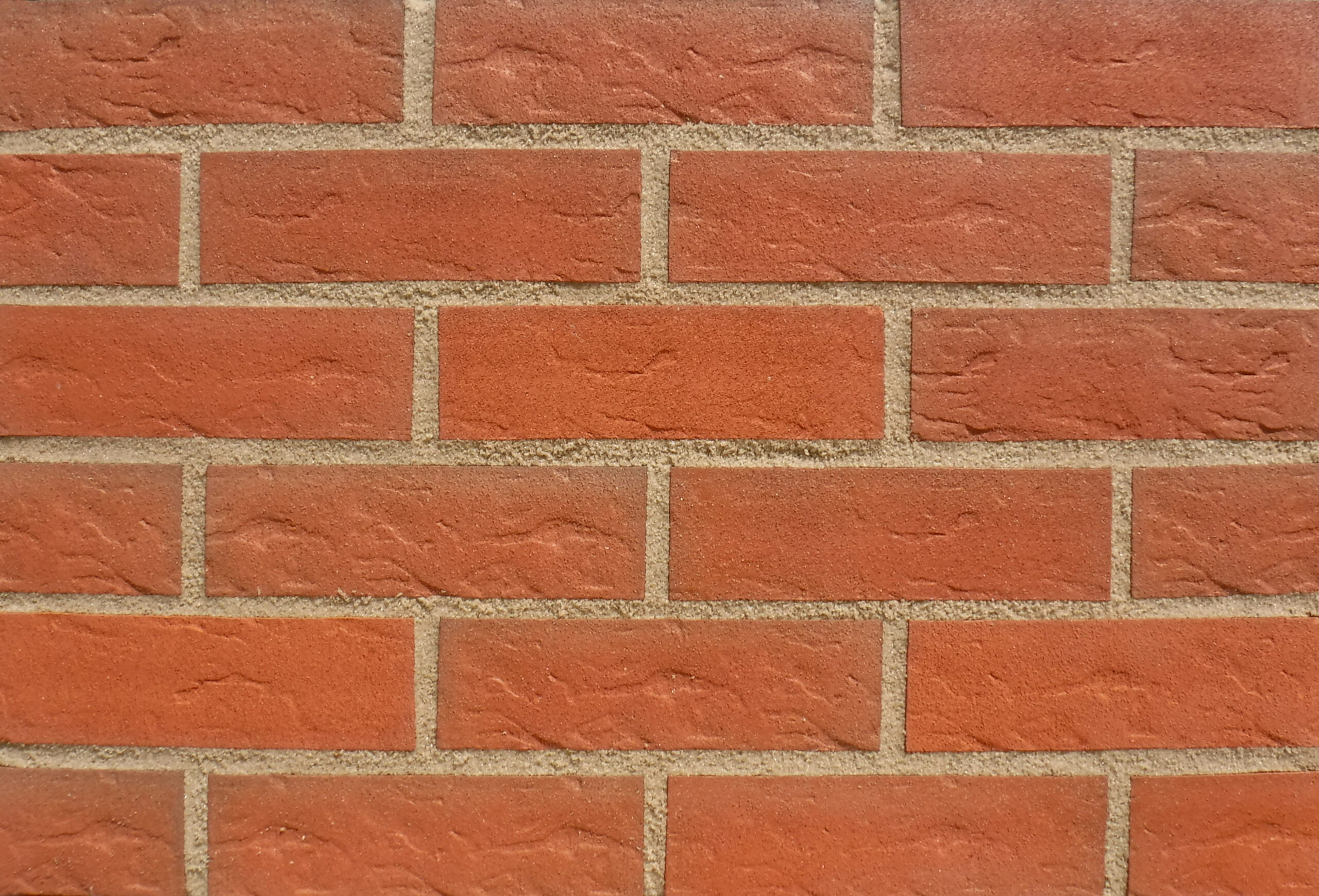 A display panel image of bricks laid in stagger bond. The brick slips are a mid red, roll textured and sanded finish. The bricks are pointed in a mid sandstone mortar