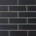 A black smooth brick slip panel. The edges of the brick are straight and square and the mortar is a mid grey A black smooth brick slip panel. The edges of the brick are straight and square and the mortar is a mid grey